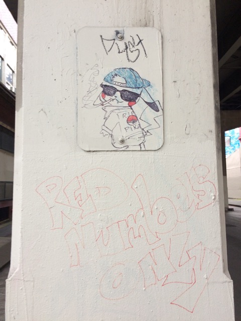 Graffiti of a cool looking Pikachu in a jean jacket and shades painted on a concrete pillar as a memorial to someone who went by Pika